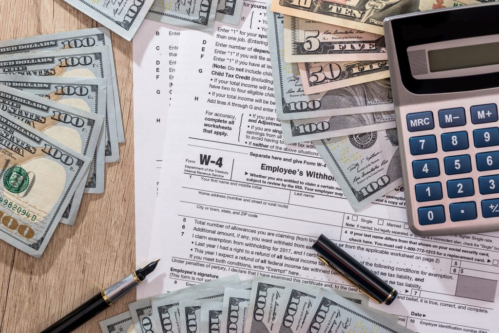 W4 Tax Form With Money Pen And Calculator On Desk